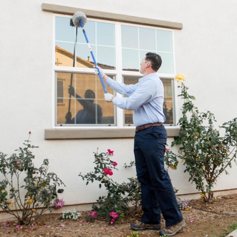 T2 Pest Services employee removing webs from the perimeter of your home